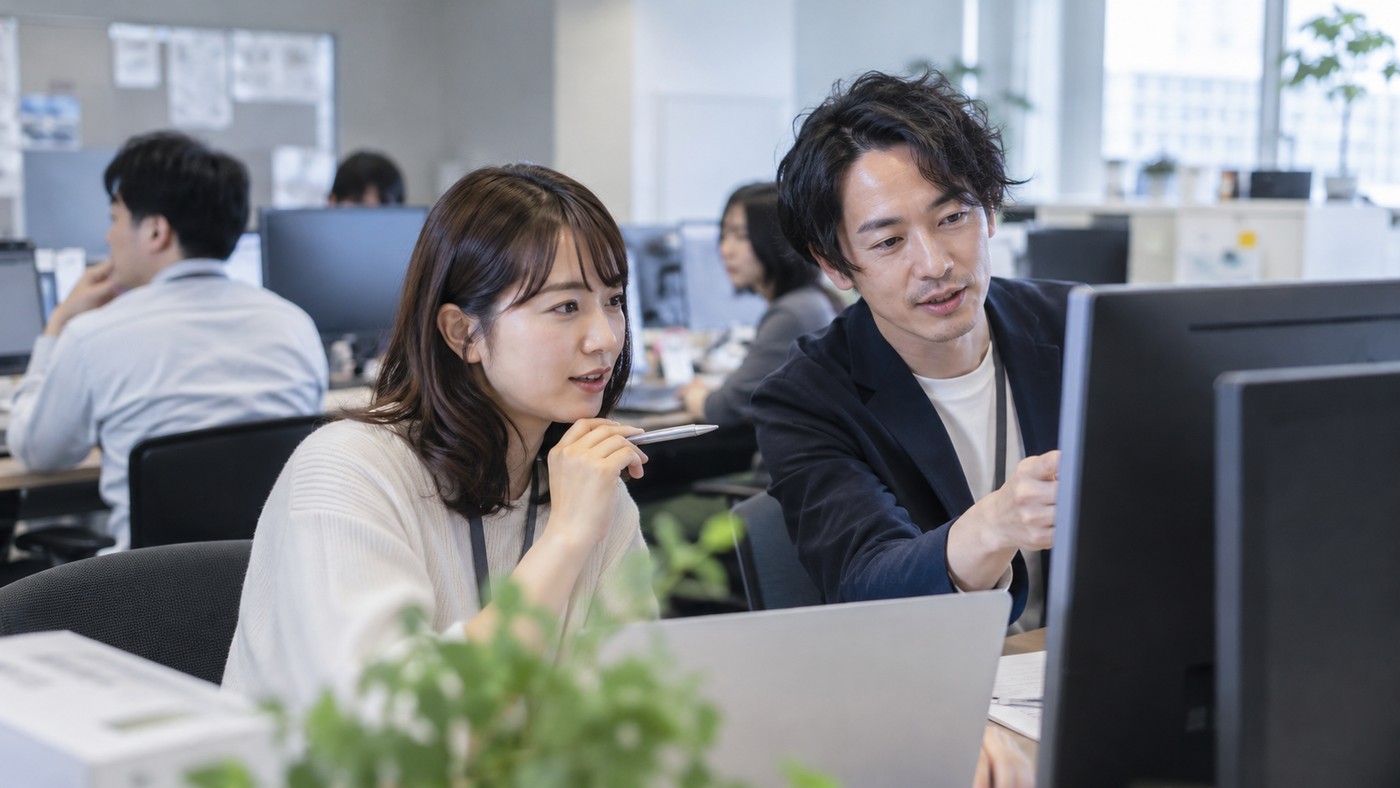 現在の会社で同僚と業務について確認しながら働く会社員
